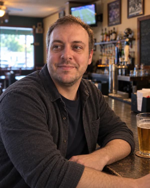 The same man seated at the bar in a natural, candid portrait