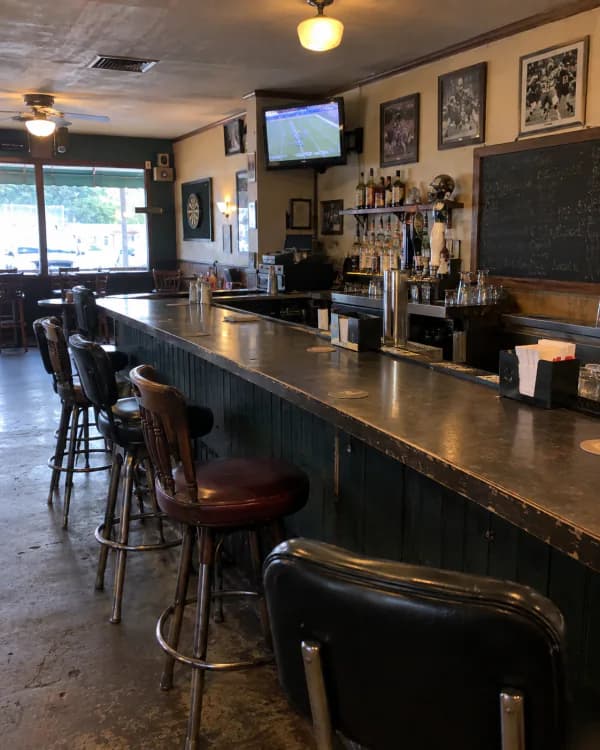 A cozy bar with a dark wood counter and warm amber lighting