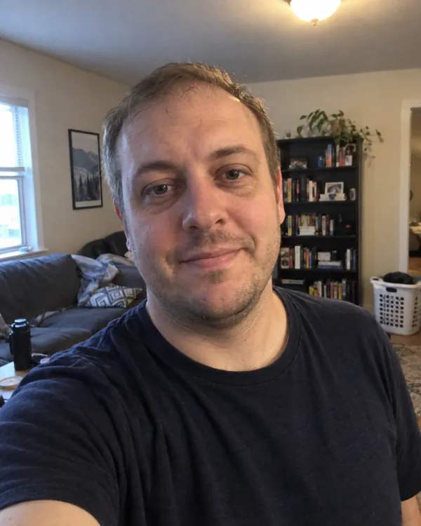 Everyday selfie of a man with wavy dark hair and a black T-shirt